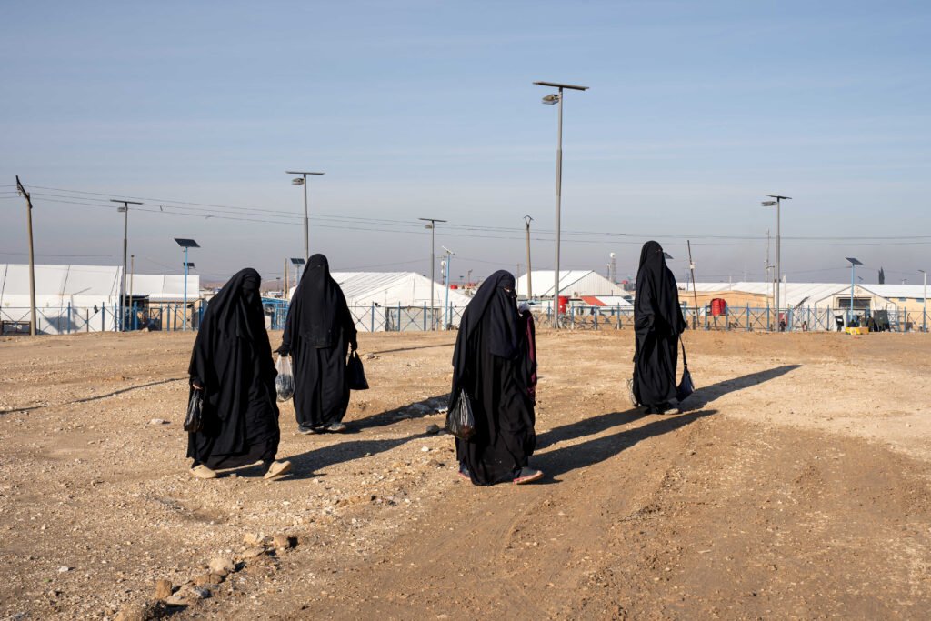 SYRIE, Camp de Al Hol, 21 janvier 2026.
Un jour après le départ des FDS du camp de Al-Hol, dans le Gouvernorat de Hassaké, la zone est maintenant sous le contrôle de l’armée syrienne.
Ici vue de l’ »annexe », zone où sont détenus les familles de combattants étrangers de l’état islamique, réputée abriter les éléments les plus radicaux et endoctrinés. 
Des femmes détenues dans l’annexe marchent entre la partie sirop-irakienne et la leur. Il semblerait que de nombreux pensionnaires de l’annexe se déplacent maintenant un peu plus librement qu’avant et se rendent dans d’autres parties du camp. Les gardes syriens assurent cependant qu’il est impossible de s’échapper de l’enceinte, divisée en plusieurs parties.